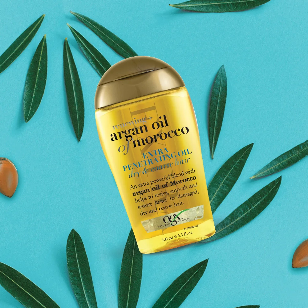 hair oil ogx argan oil morocco trên nền xanh biển có lá cây