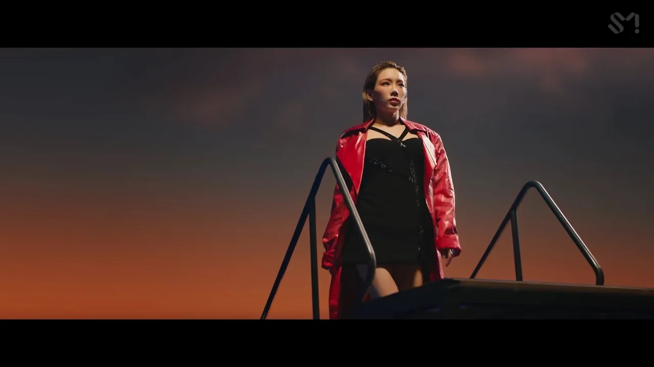 Ca sĩ Taeyeon mặc đầm đen, áo khoác đỏ trong MV Spark