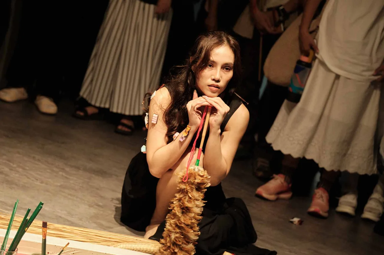 cô gái đang cầm chổi lông gà trong triển lãm nghệ thuật vài "a" lần