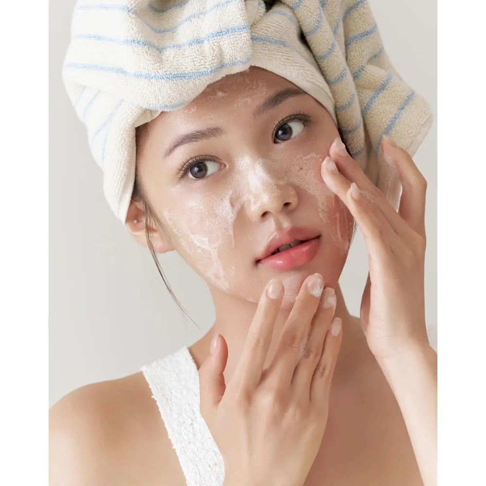 Cô gái thoa sữa rửa mặt lên mặt.