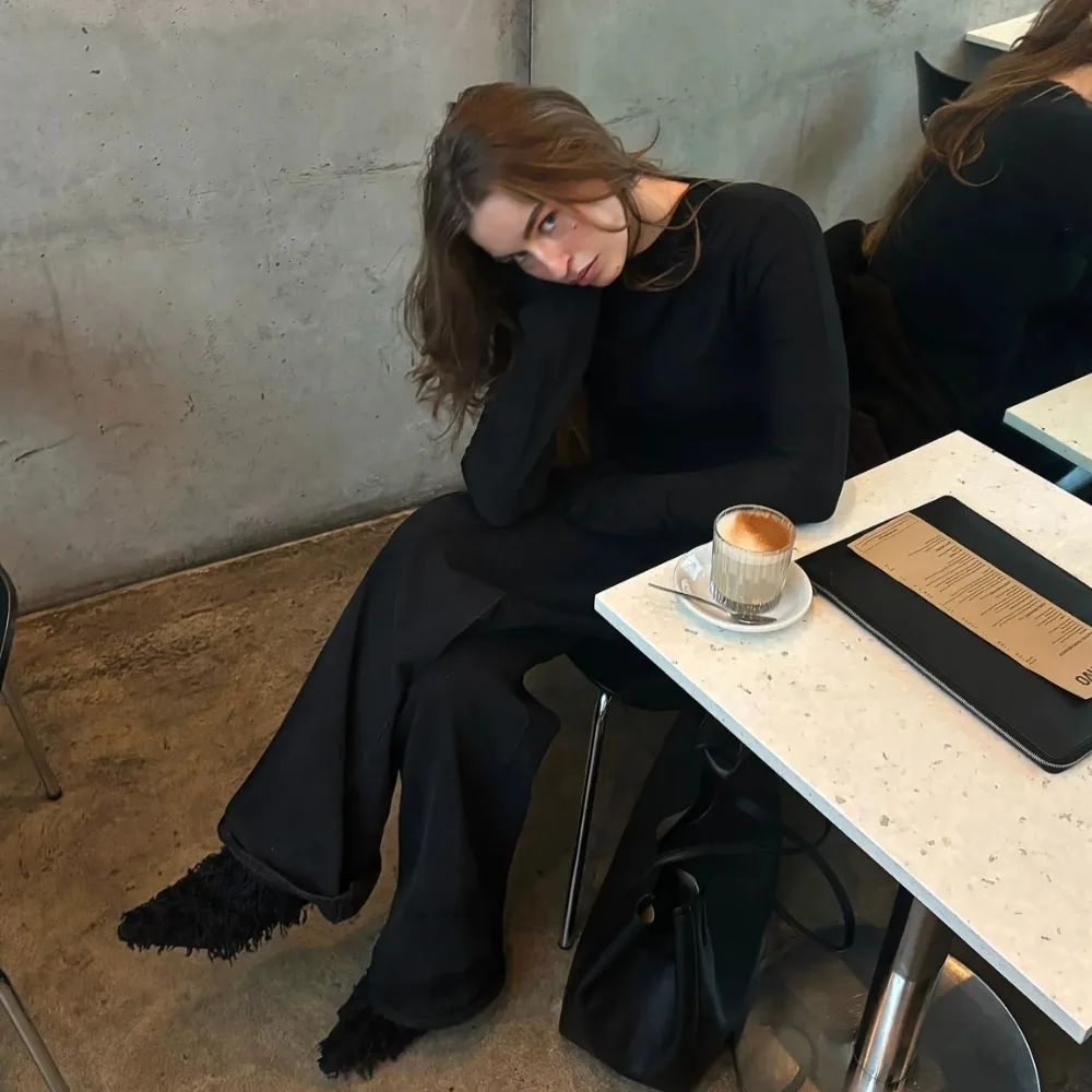 cô gái ngồi bên bàn với ly latte