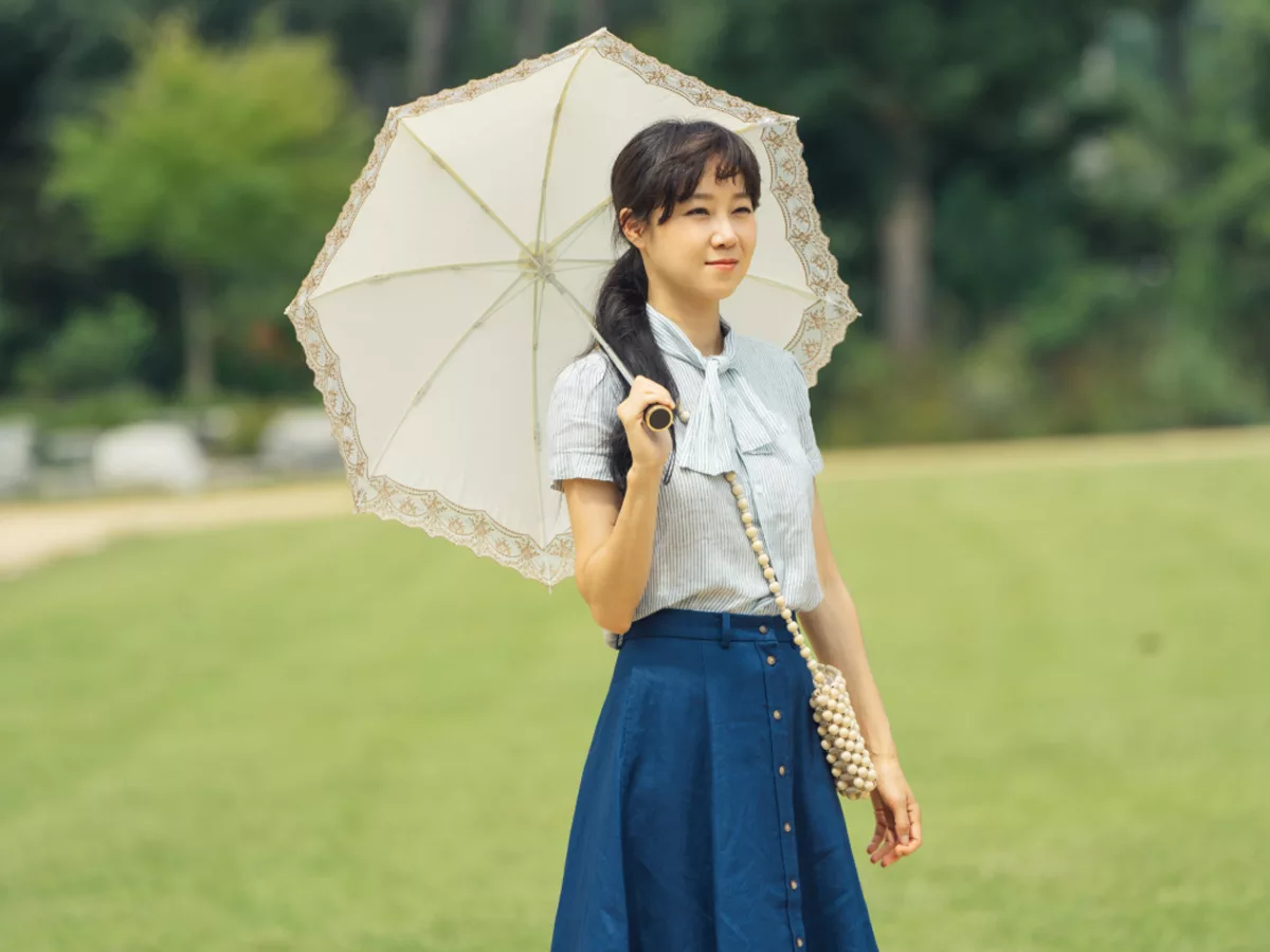 Gong Hyo Jin mặc áo sơ mi xanh, chân váy xanh, cầm dù trong phim Hàn Quốc When The Camellia Blooms