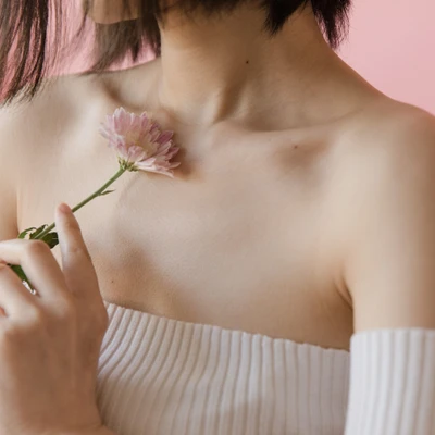 cô gái mang áo hở vai cầm nhánh hoa