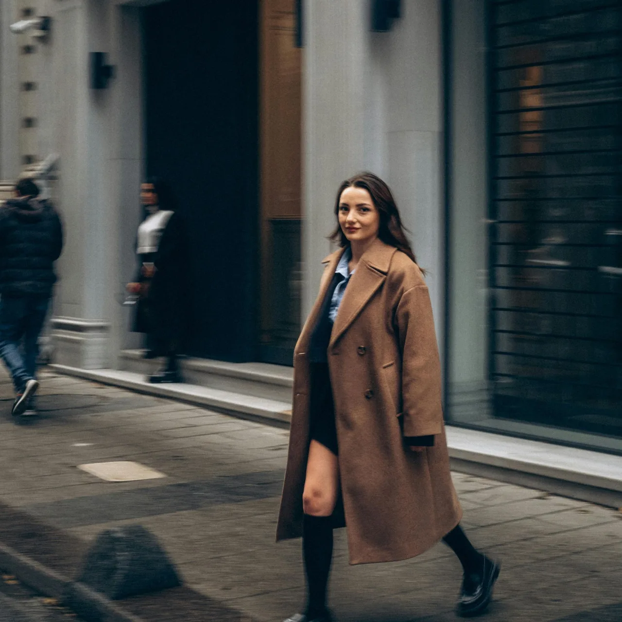 cô gái mặc áo trenchcoat bước đi trên phố đón nhận dấu hiệu tích cực của vũ trụ