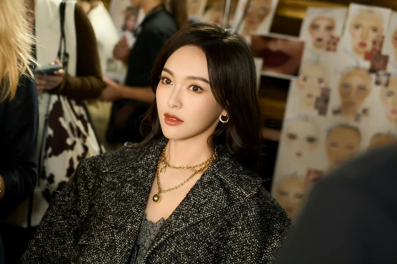Đường Yên mặc áo blazer màu xám, đeo dây chuyền màu vàng kiểu layer và xõa tóc thẳng để makeup