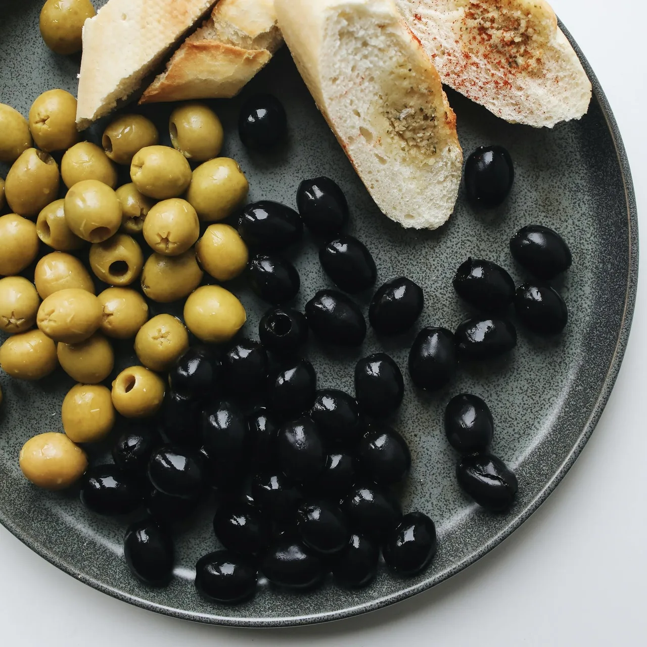 Đĩa đựng những quả olive tươi màu đen bóng.