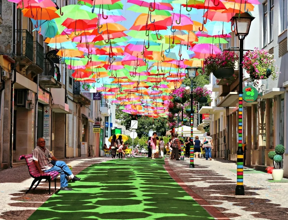 9 con đường đẹp chỉ có ở chốn thần tiên Những chiếc dù này lần đầu xuất hiện tại Agueda vào năm 2012. Những chiếc dù màu sắc này được trang trí cũng như giúp người đi bộ tránh khỏi cái nắng gắt ở Bồ Đào Nha.