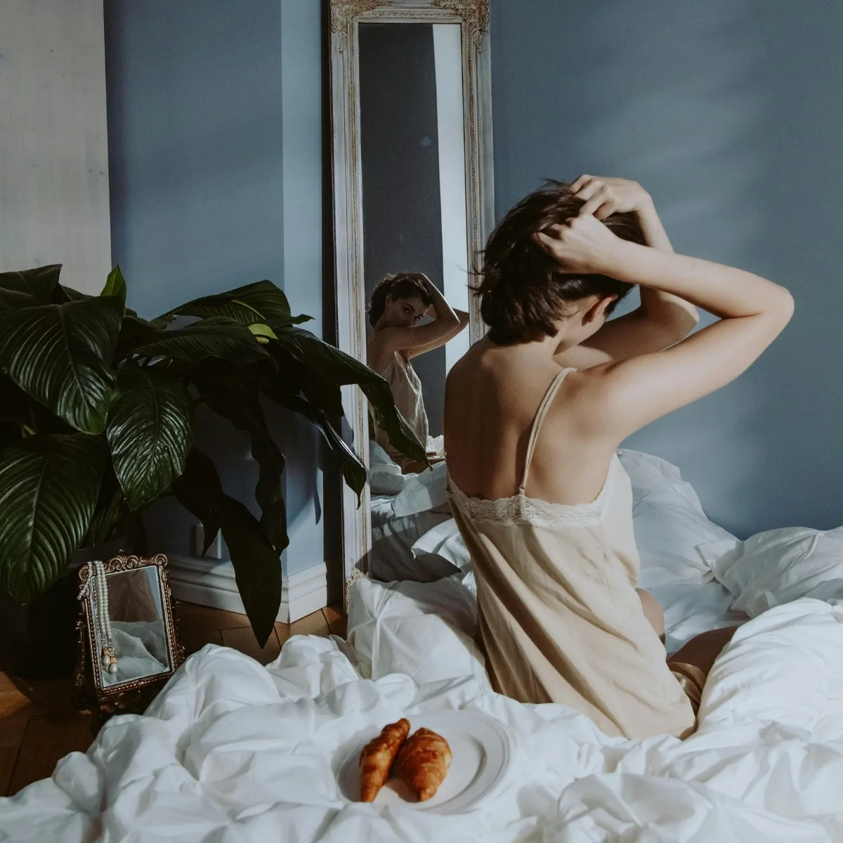 Cô gái trí tuệ ngồi trên giường soi gương cột tóc