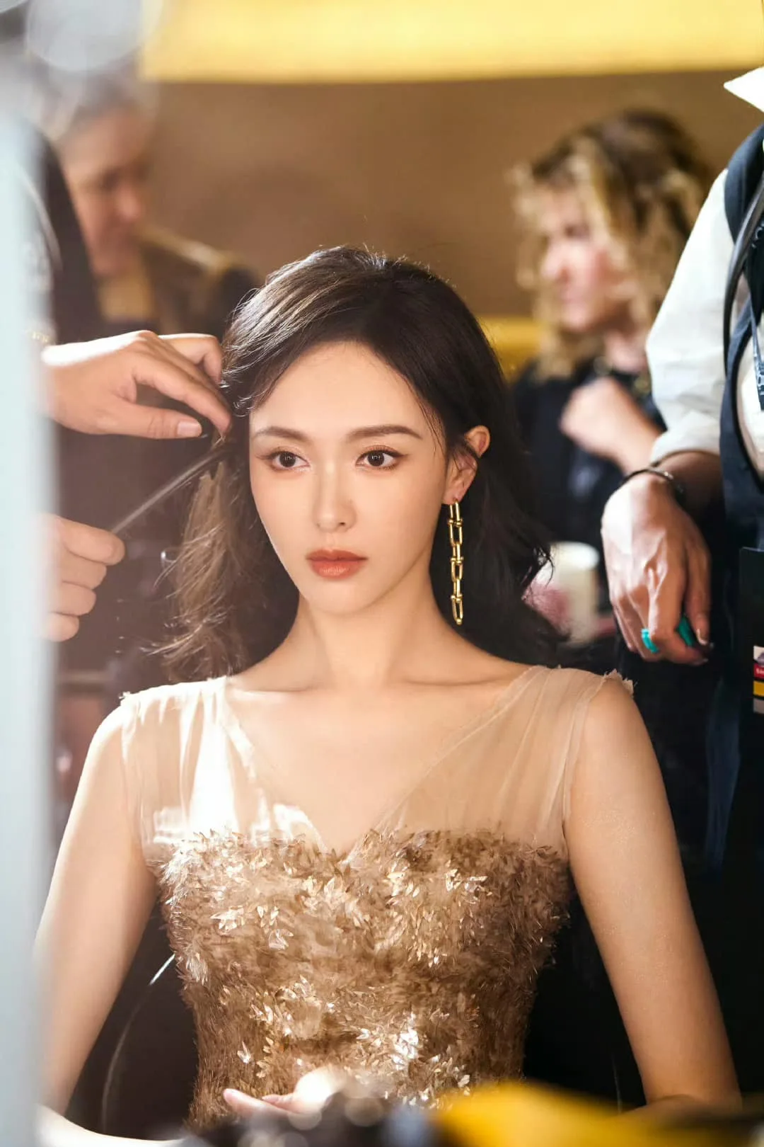 Đường Yên mặc đầm sequin, đeo bông tai dài và ngồi trước gương để makeup