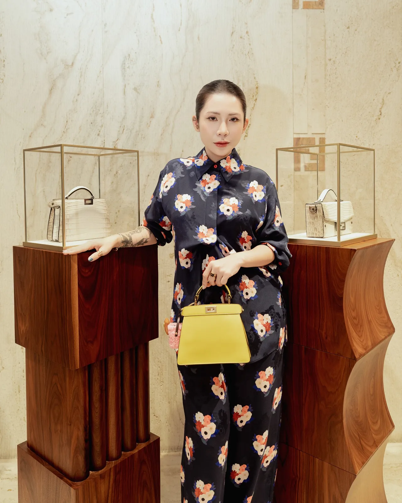 Lâm Thúy Nhàn lựa chọn bộ trang phục lụa mềm mại với họa tiết hoa ấn tượng trên nền tối, khéo léo tạo sự tương phản đầy sức sống bằng chiếc túi Peekaboo sắc vàng chanh tươi mới, thể hiện tinh thần "trị liệu" qua màu sắc của Fendi.