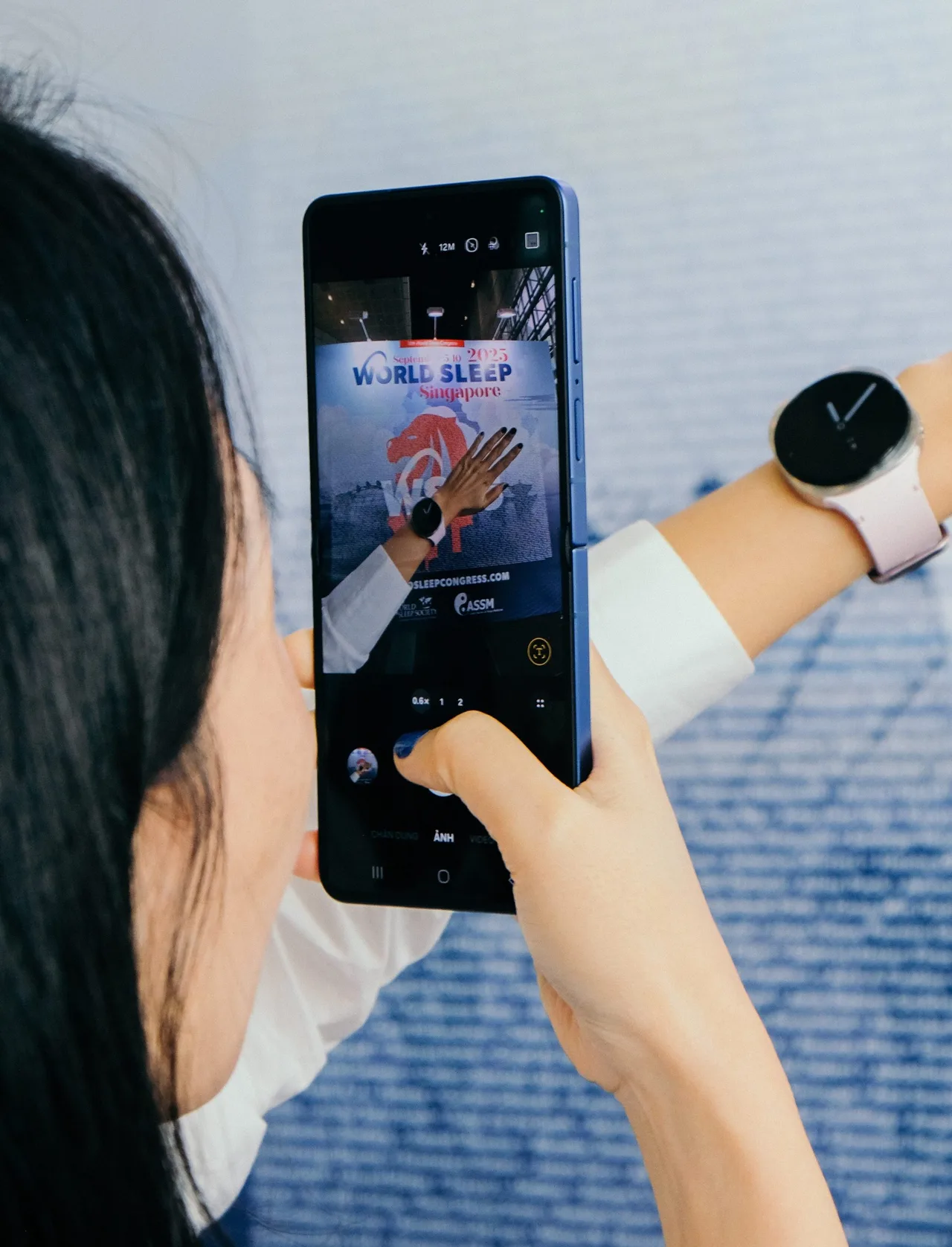 Cô gái cầm điện thoại chụp ảnh đồng hồ Samsung Galaxy Watch8 đang đeo trên tay