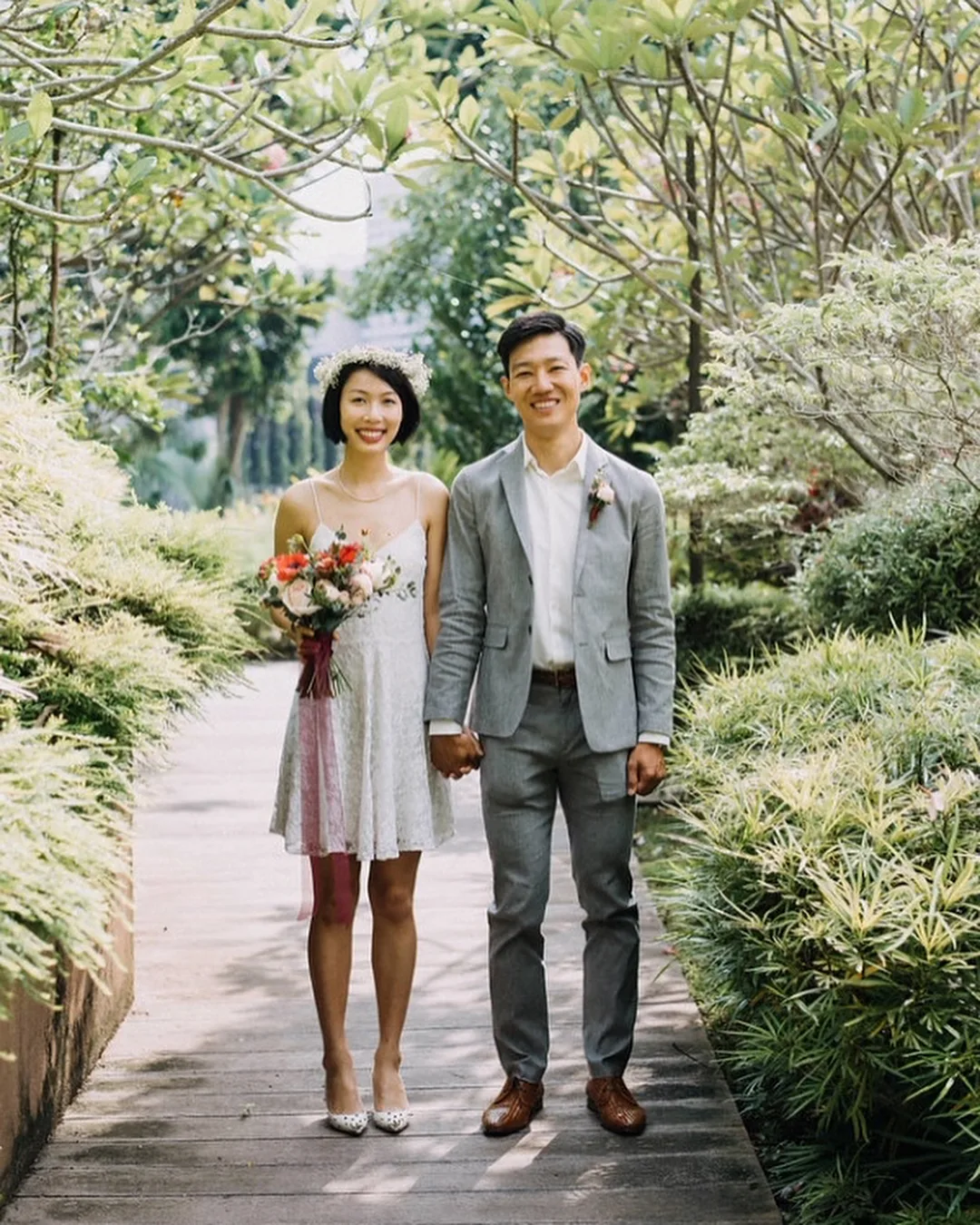 cô dâu mặc đầm cưới ngắn cầm bó hoa cưới kiểu tự nhiên nắm tay chú rể