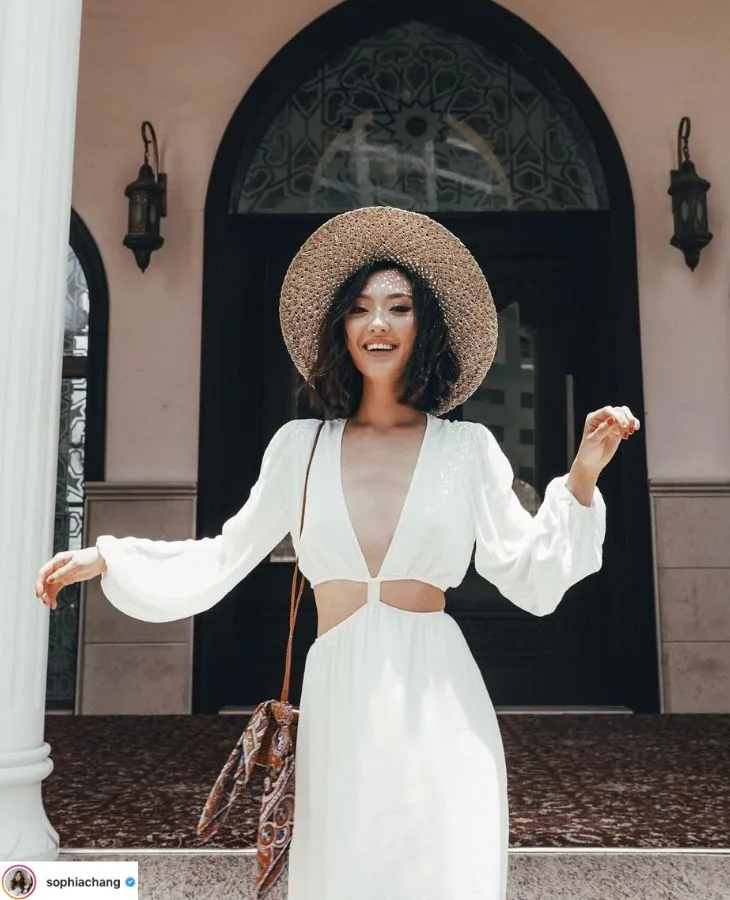 sophia chang mặc đầm trắng tay dài khoét eo nón cói rộng vành