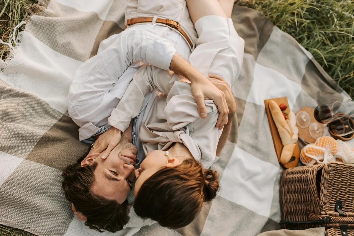 Cặp đôi ôm nhau nằm trên thảm picnic