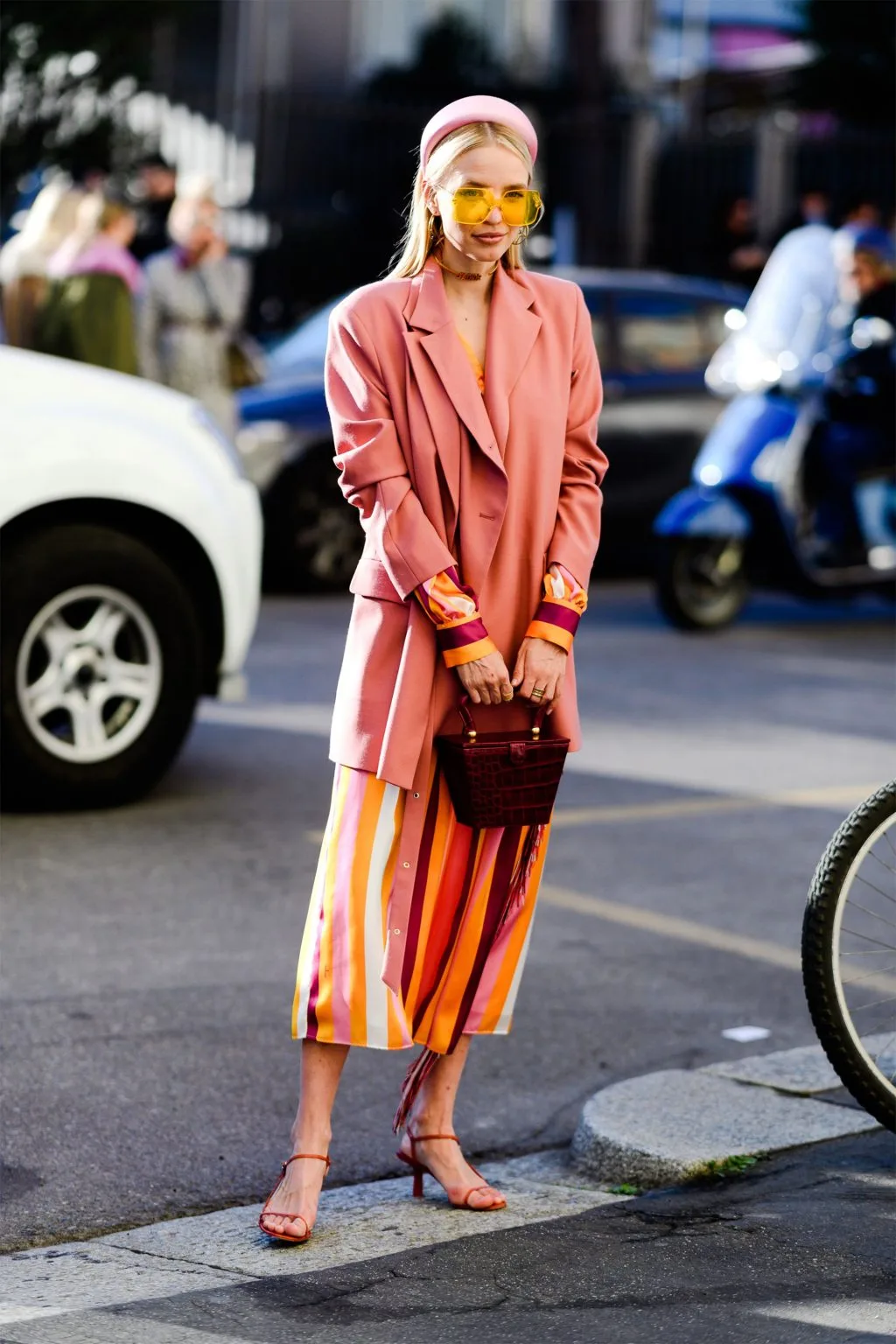 fashionista diện blazer hồng, băng đô hồng, kính mát bản lớn vàng, đầm kẻ sọc và túi xách hình học