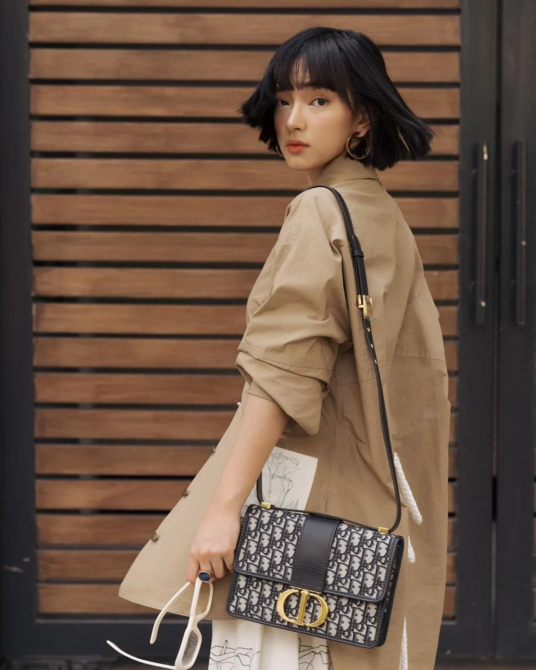 Châu Bùi mặc áo khoác be đeo túi Dior