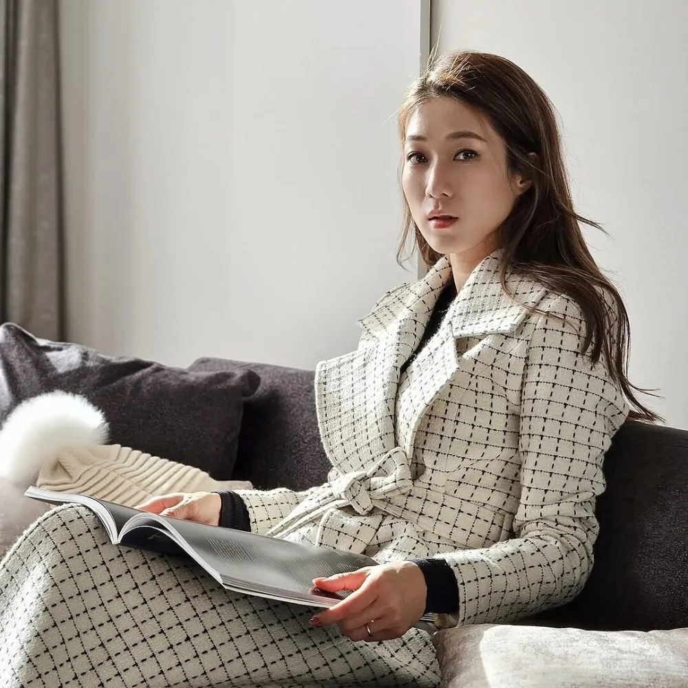 Nữ diễn viên ngồi trên sofa và cầm cuốn tạp chí.