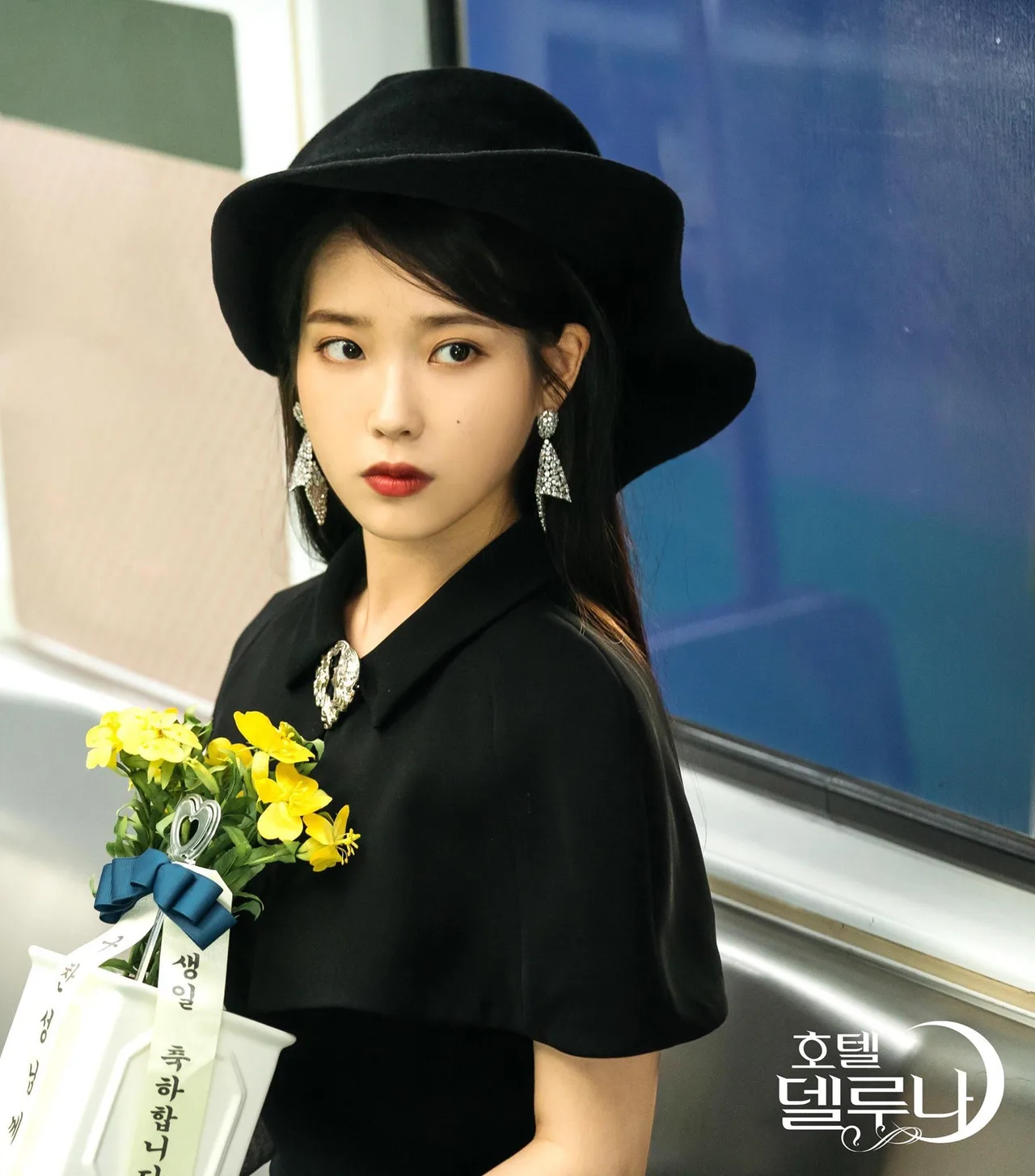 iu đầm đen mũ đen hoa vàng