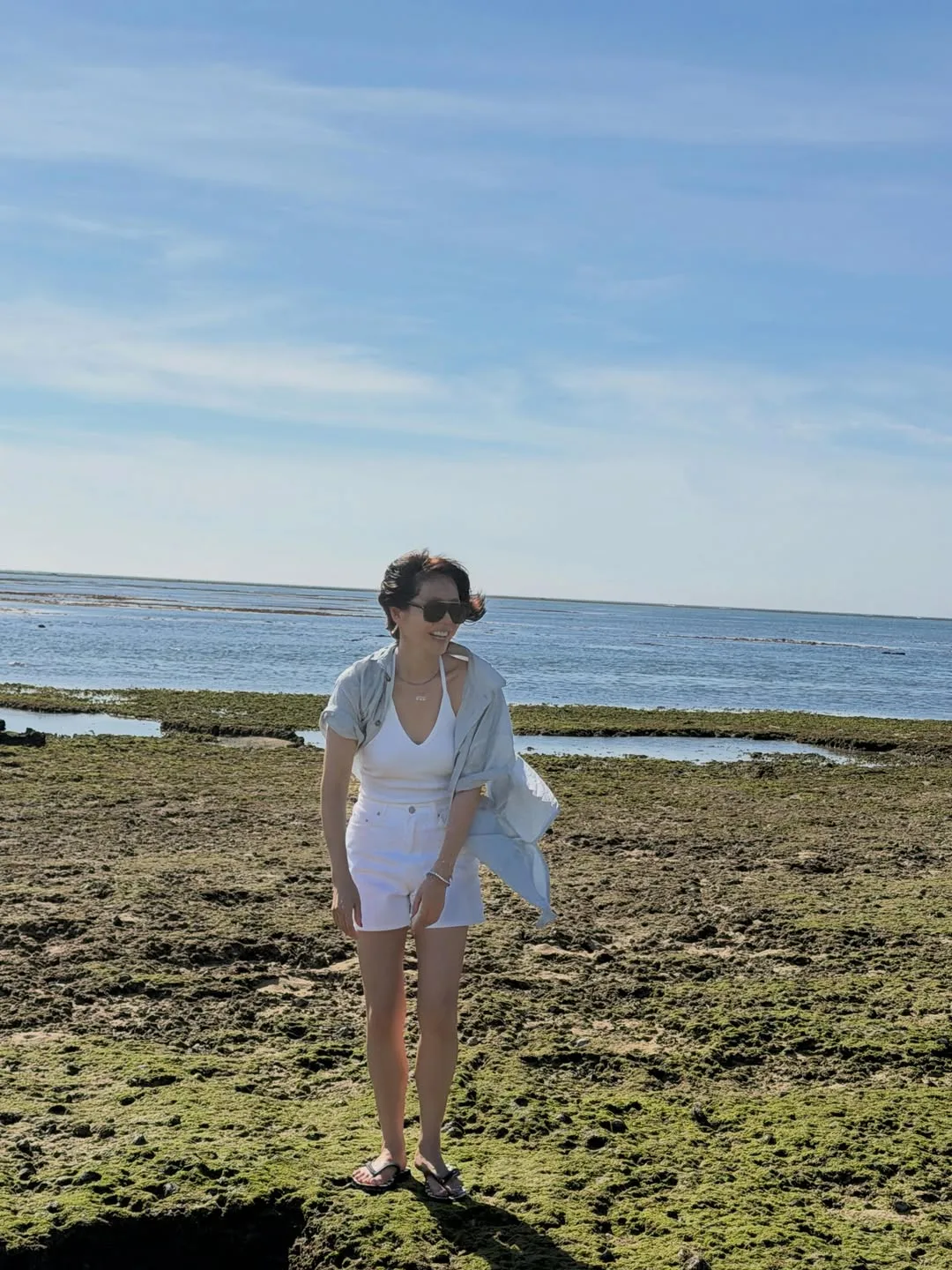 Son Ye Jin diện áo cổ yếm, quần shorts jeans đồng màu trắng và chiếc áo sơ mi mỏng khoác ngoài đầy ngẫu hứng.