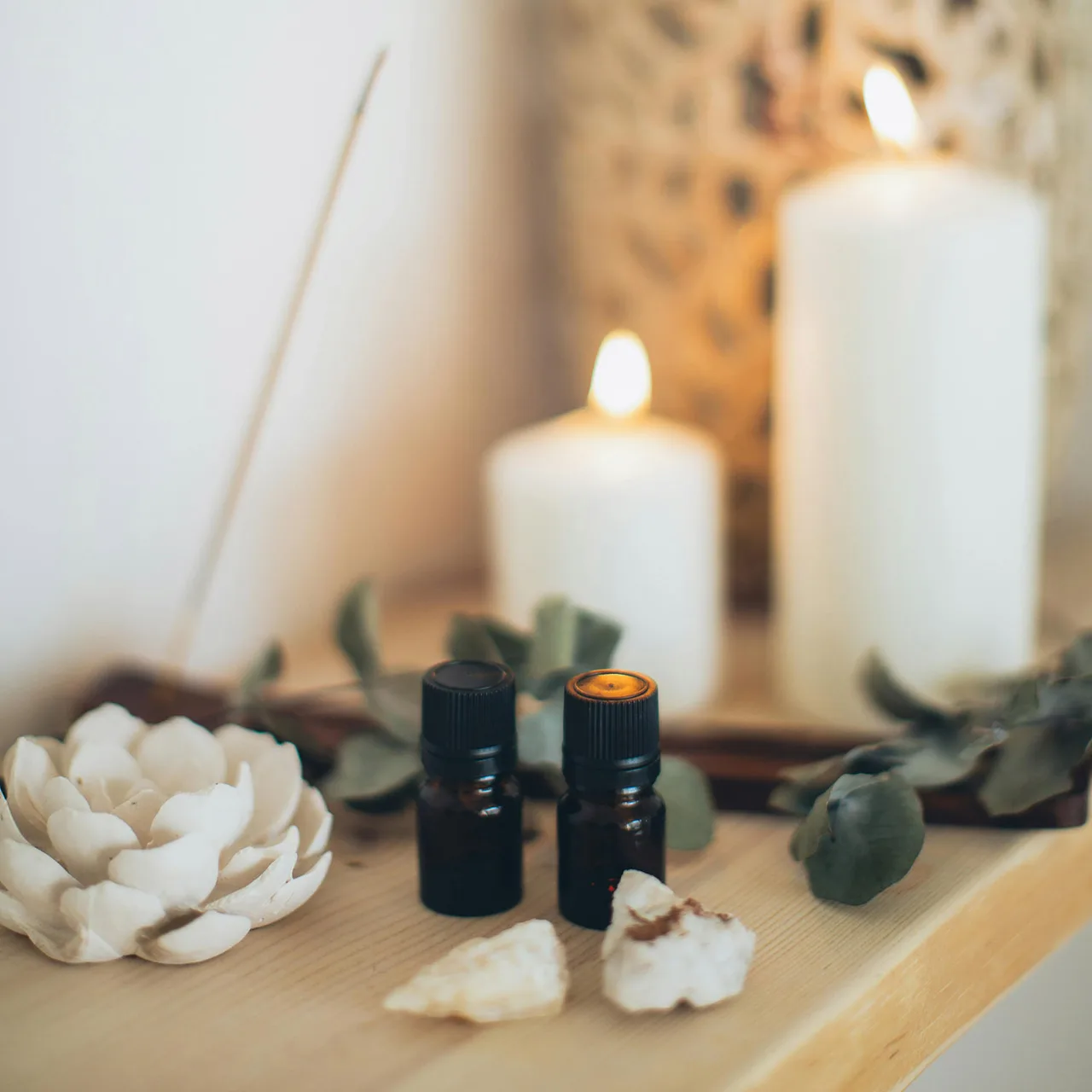 Tinh dầu đặt cạnh nến trắng dùng để thanh tẩy năng lượng xấu khỏi ngôi nhà