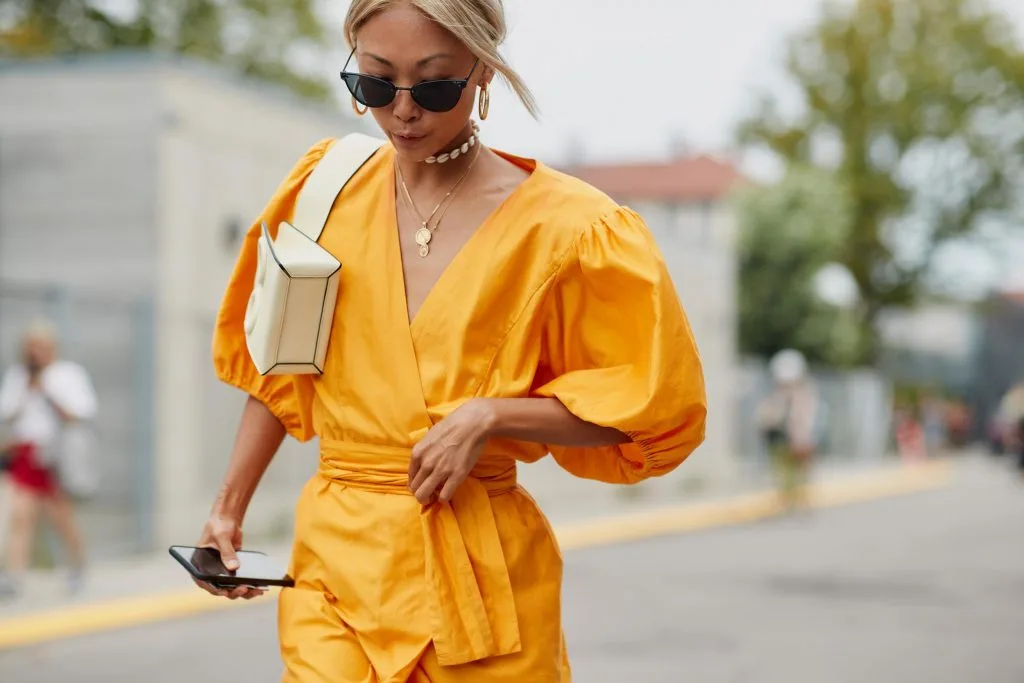 Fashionista mặc chiếc váy vàng cùng túi xách trắng và kính mắt đen