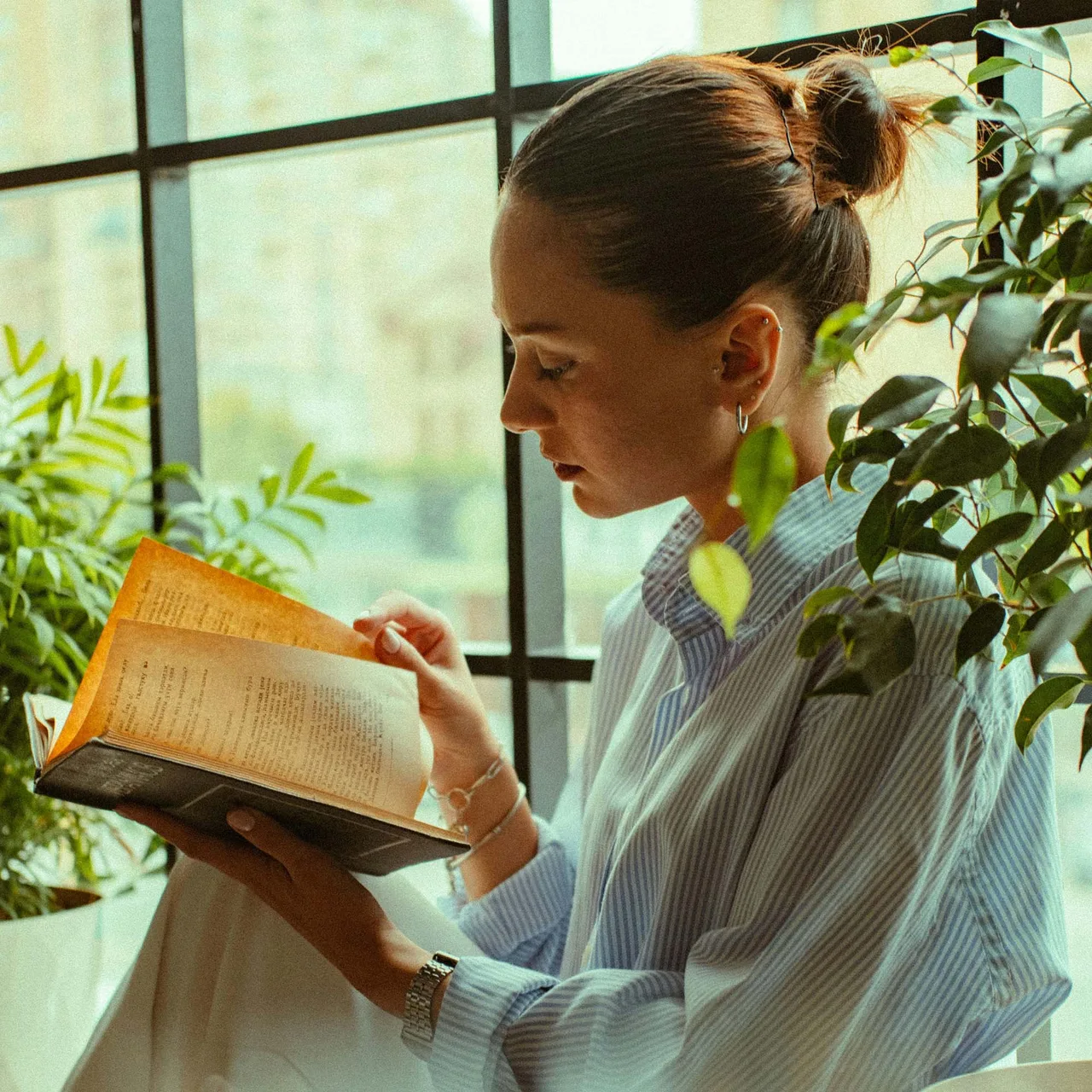 người phụ nữ mặc áo sơ mi đang đọc sách