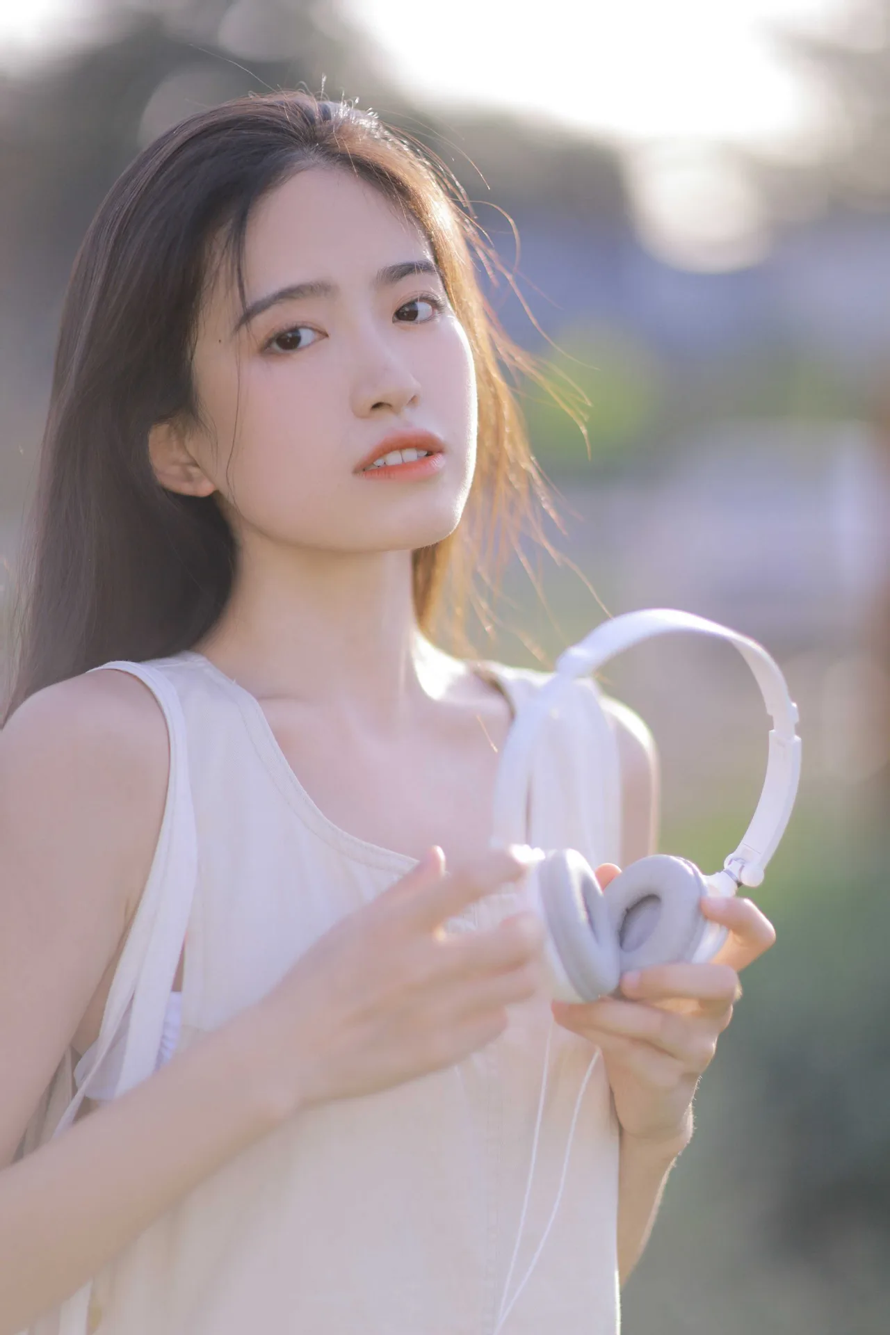 cô gái hướng nội mặc váy trắng cầm tai nghe