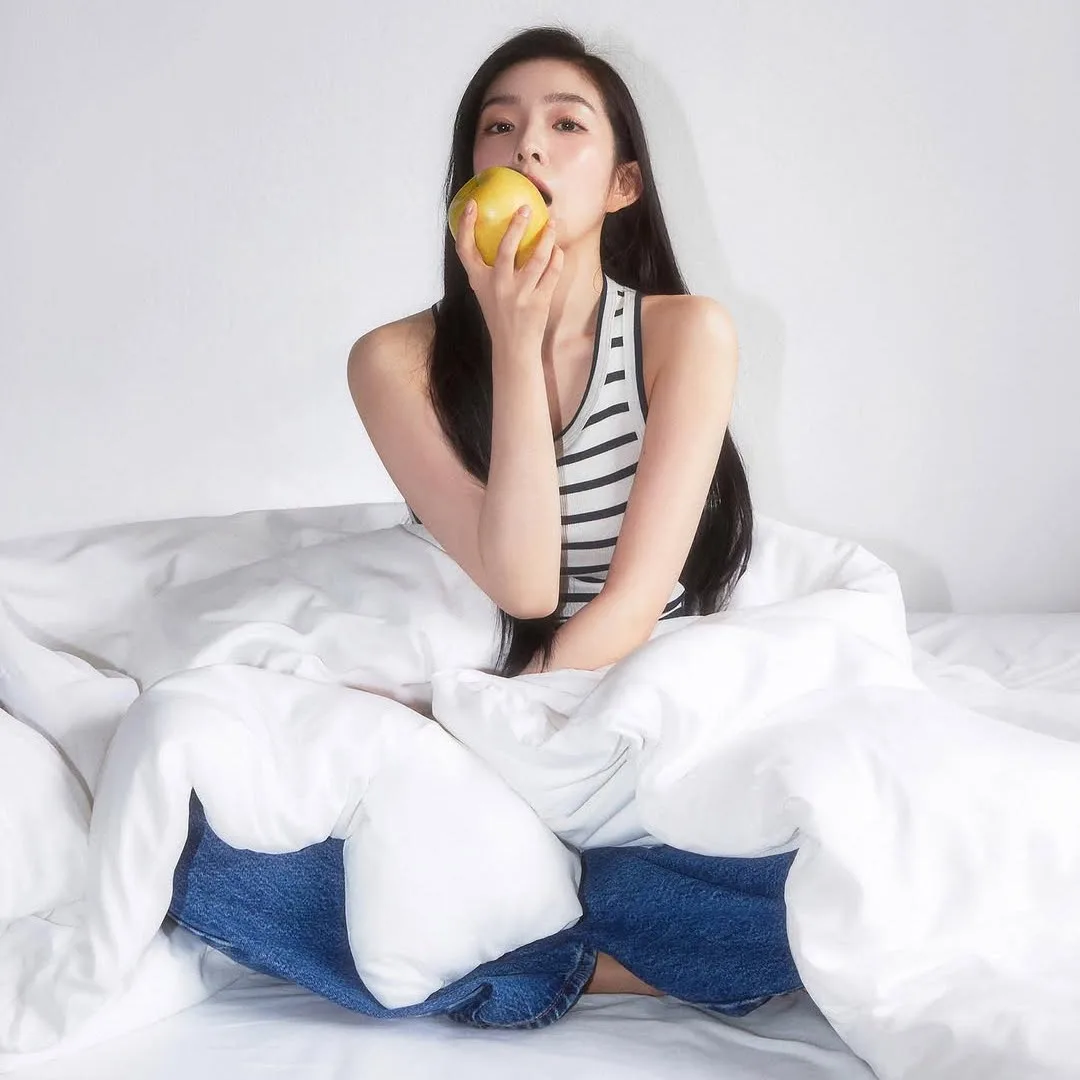 Cô gái ngồi trên giường ăn trái cây - chế độ ăn uống lành mạnh giúp tăng cường sức đề kháng tự nhiên