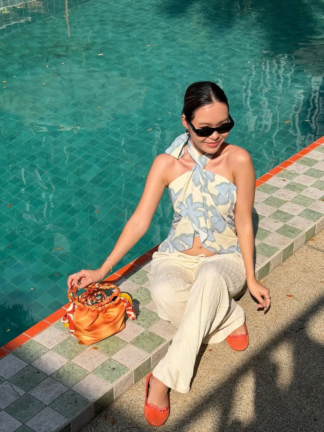 Đôi giày mules màu cam rực rỡ thắp sáng set đồ đen tối giản, biến lựa chọn an toàn trở nên có gu hơn.