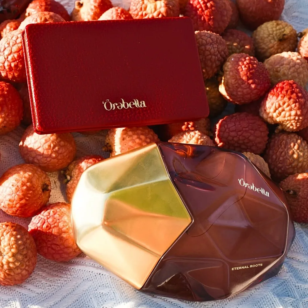 Lọ nước hoa Orebella Eternal Roots đặt cạnh những quả vải