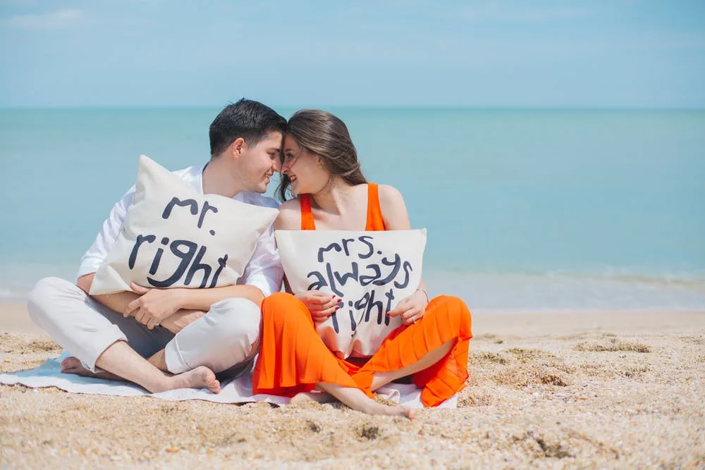 cặp đôi ôm gối trên bờ biển