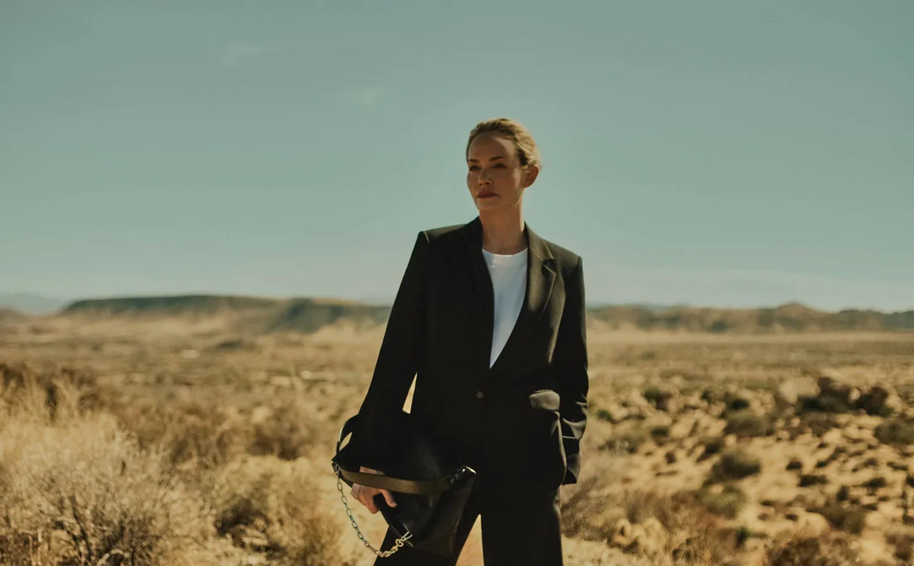Amber Valletta in black suit holding black cactus leather K:Kushion from the collaboration campaign with Karl Lagerfeld