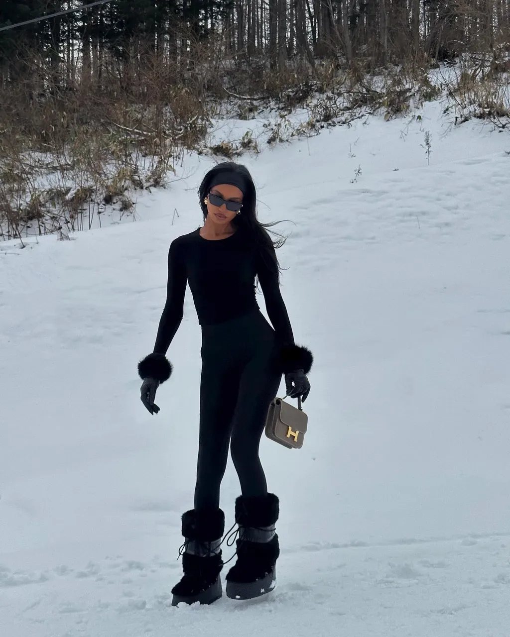 Snow boots màu đen được chụp trên nền tuyết dày, tạo độ tương phản thú vị giữa sắc tối và bề mặt trắng xốp.