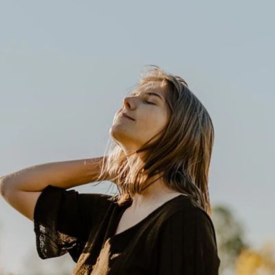Cô gái tóc ngắn mặc áo đen, ngửa cổ đón ánh nắng mặt trời buổi sớm với gương mặt thư thái.