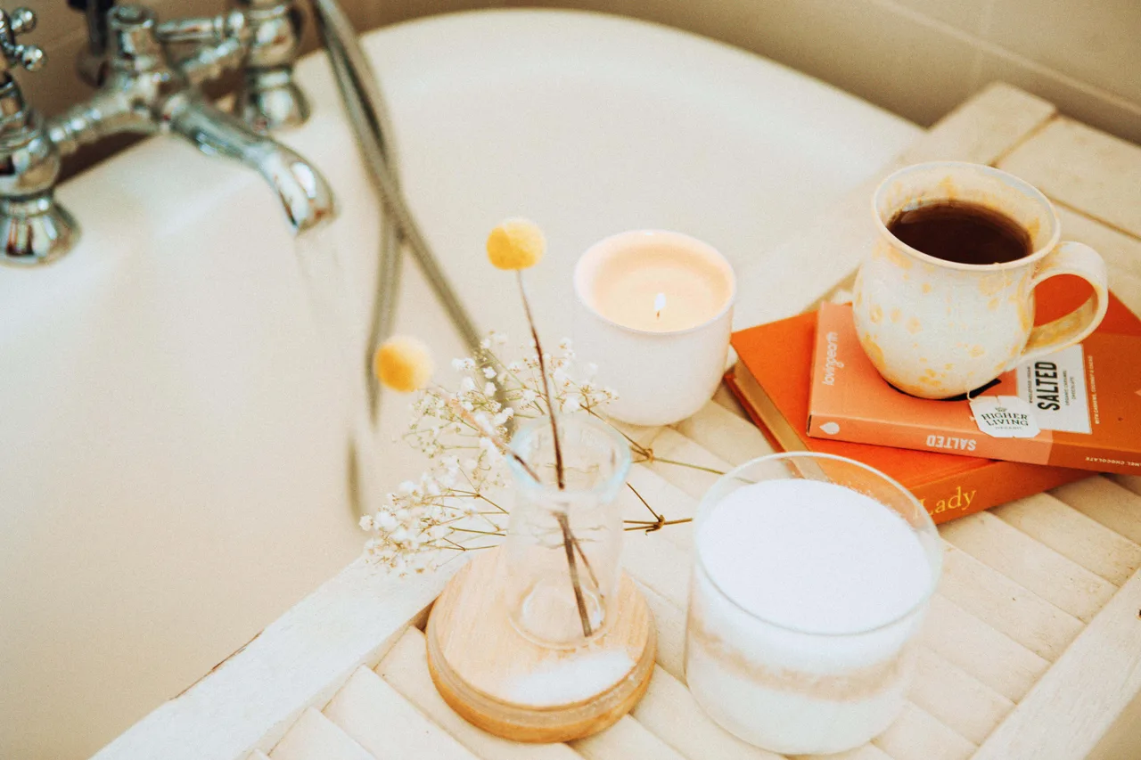 bồn tắm, vòi sen, sách và nến thơm