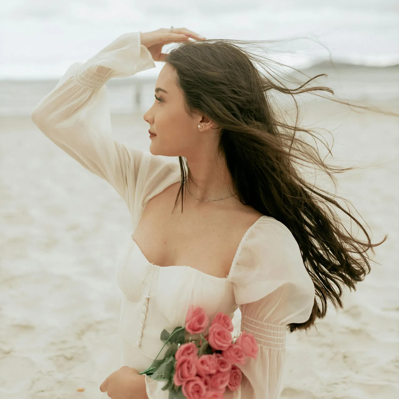 Cô gái ôm bó hoa hồng ở bãi biển suy nghĩ khi nào nên tin vào trực giác