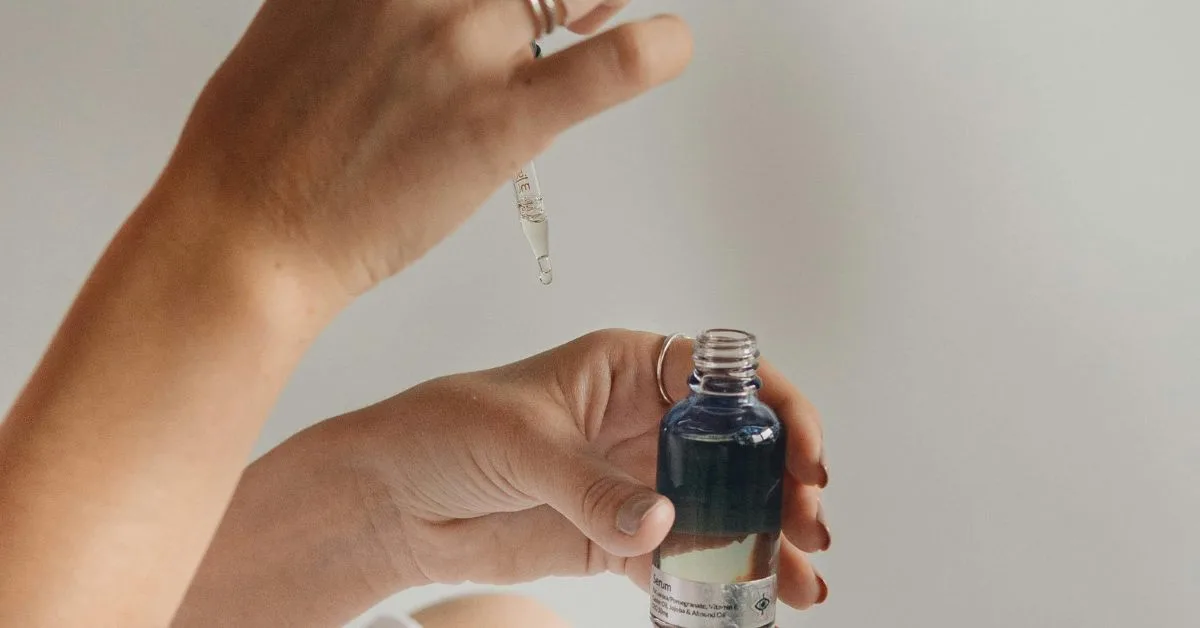 Tay cầm lọ serum và nhỏ từng giọt tinh chất từ ống dropper - mỹ phẩm phục hồi khi du lịch