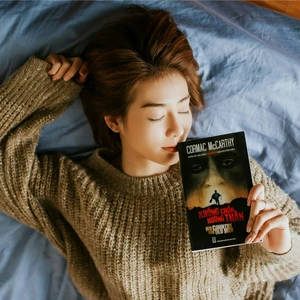 Cô gái cầm sách nằm trên giường trong giấc ngủ