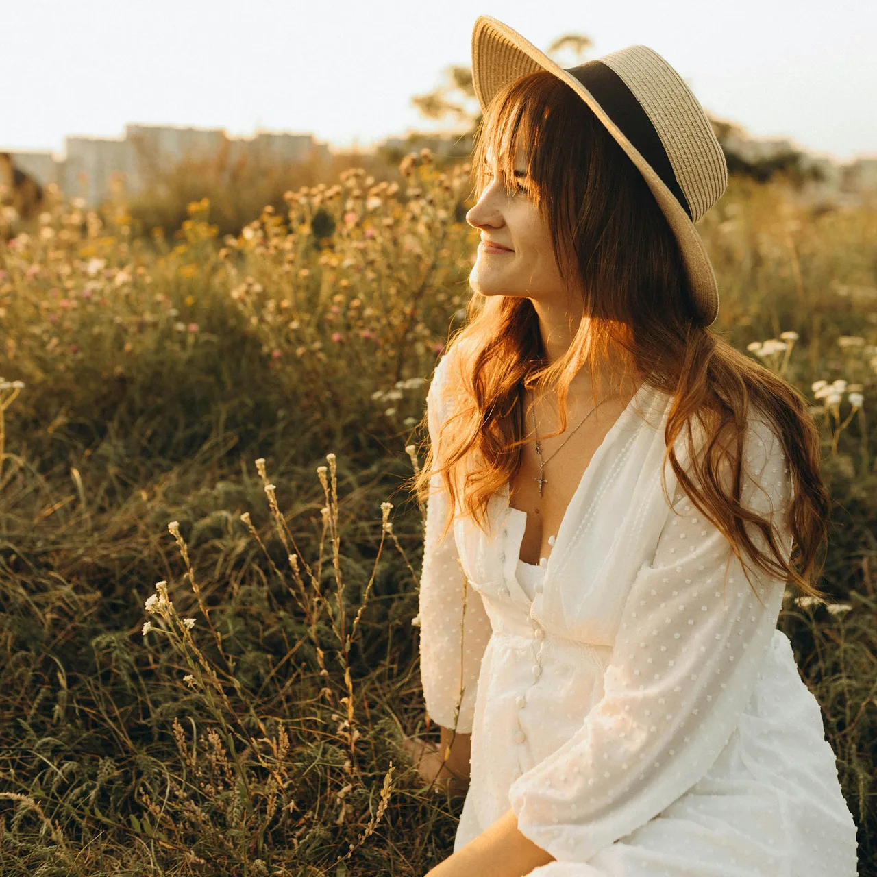 cô gái váy trắng ngồi giữa cánh đồng đang hạnh phúc