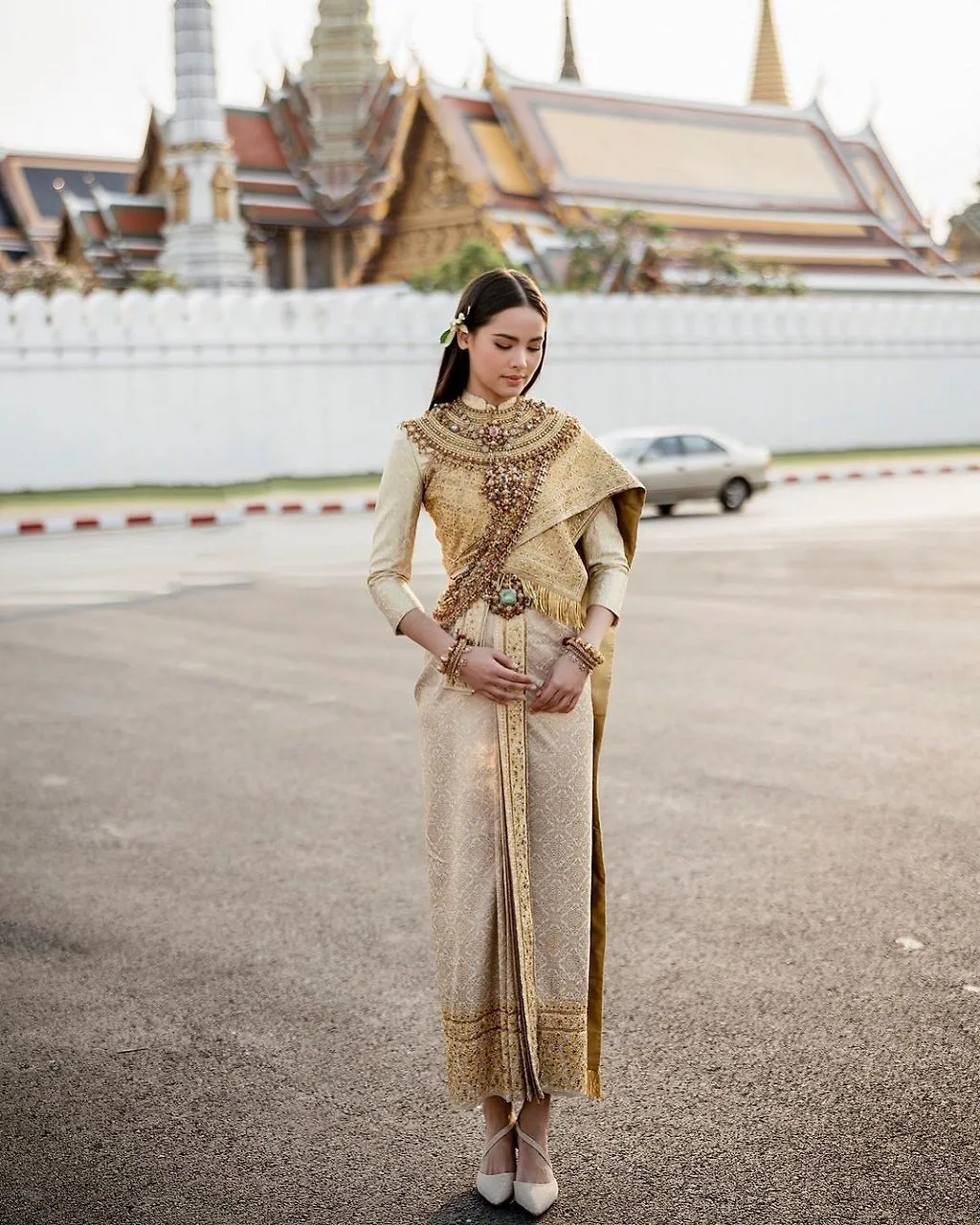 Diễn viên Urassaya Sperbund mặc váy dài và áo vàng có hoạ tiết vắt chéo vai