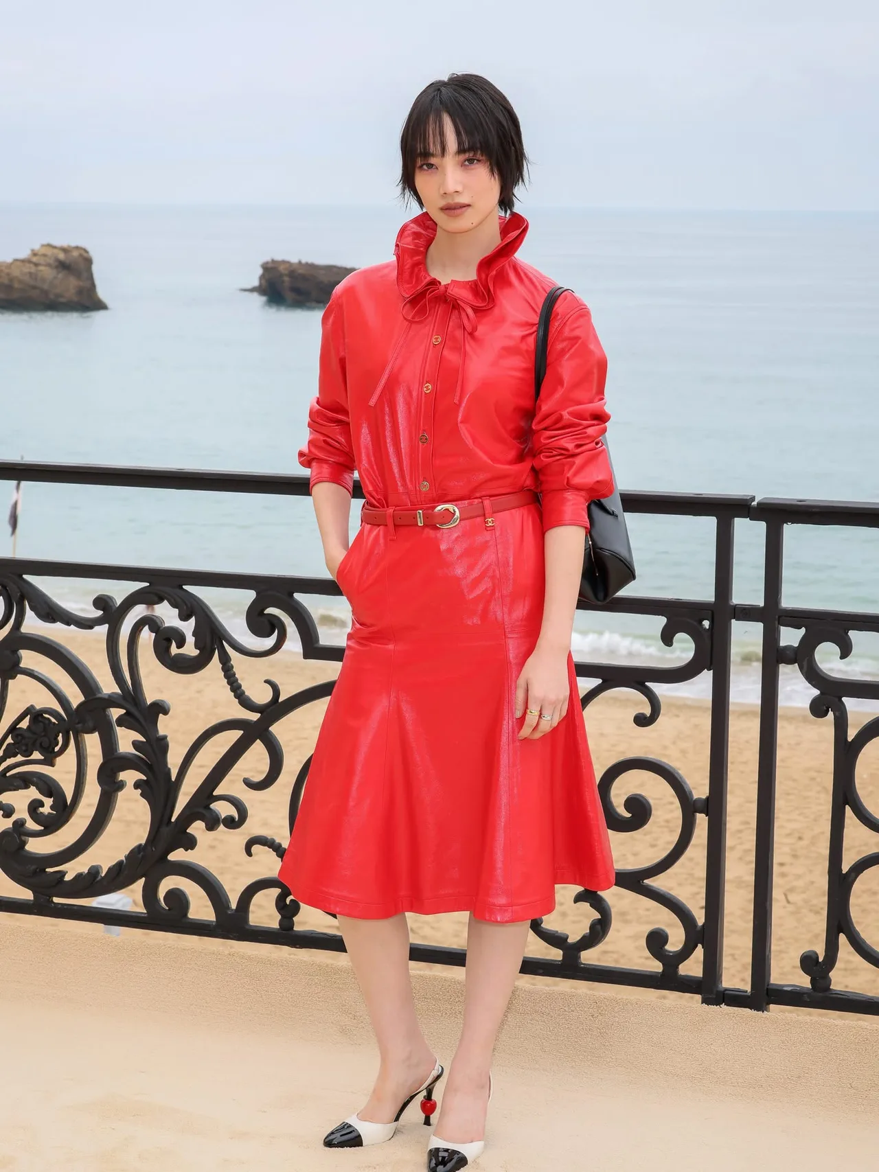 Nana Komatsu chọn một thiết kế nguyên cây đỏ bằng chất liệu da bóng cao cấp. Phần áo có chi tiết cổ xếp bèo điệu đà kết hợp cùng hàng khuy vàng sang trọng.