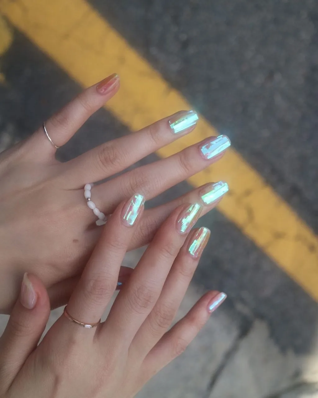 nail đẹp - bàn tay đeo nhẫn màu bạc, duỗi thẳng ra và sơn móng hologram