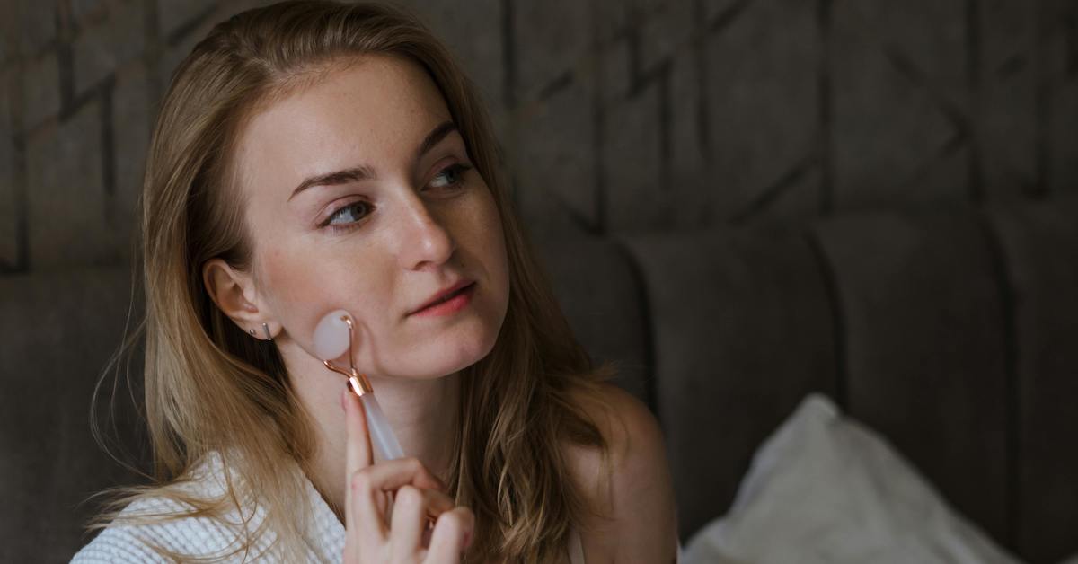 Cô gái sử dụng dụng cụ massage mặt trong chu trình chăm sóc da ban đêm