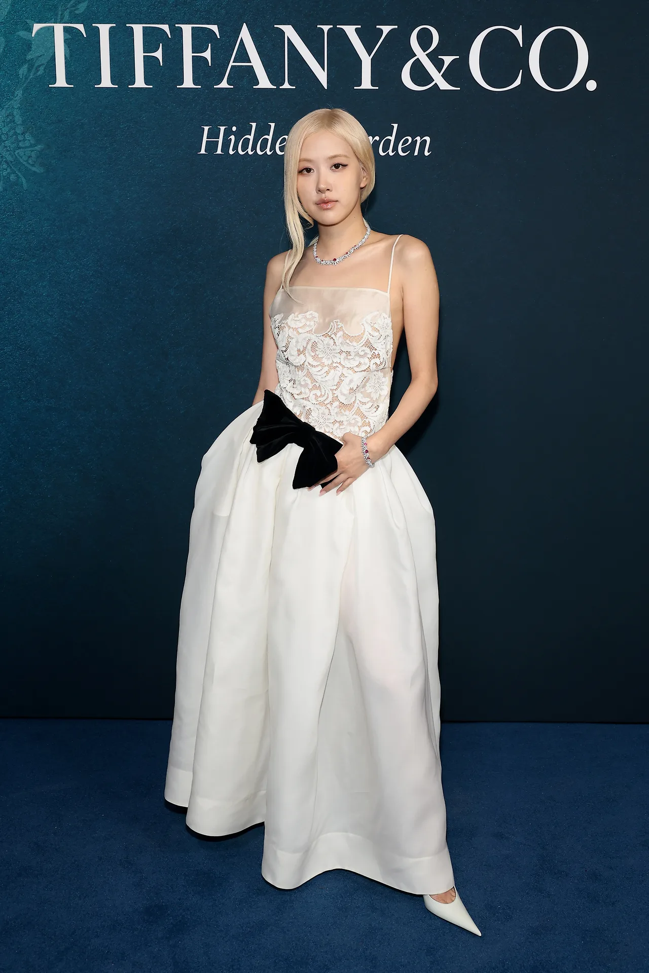 Rosé: Nàng đại sứ toàn cầu thu hút mọi ánh nhìn trong chiếc váy trắng đính ren tinh xảo với điểm nhấn nơ đen bản to ở eo, kết hợp cùng vòng cổ và vòng tay kim cương lấp lánh điểm xuyết đá quý màu hồng đỏ.
