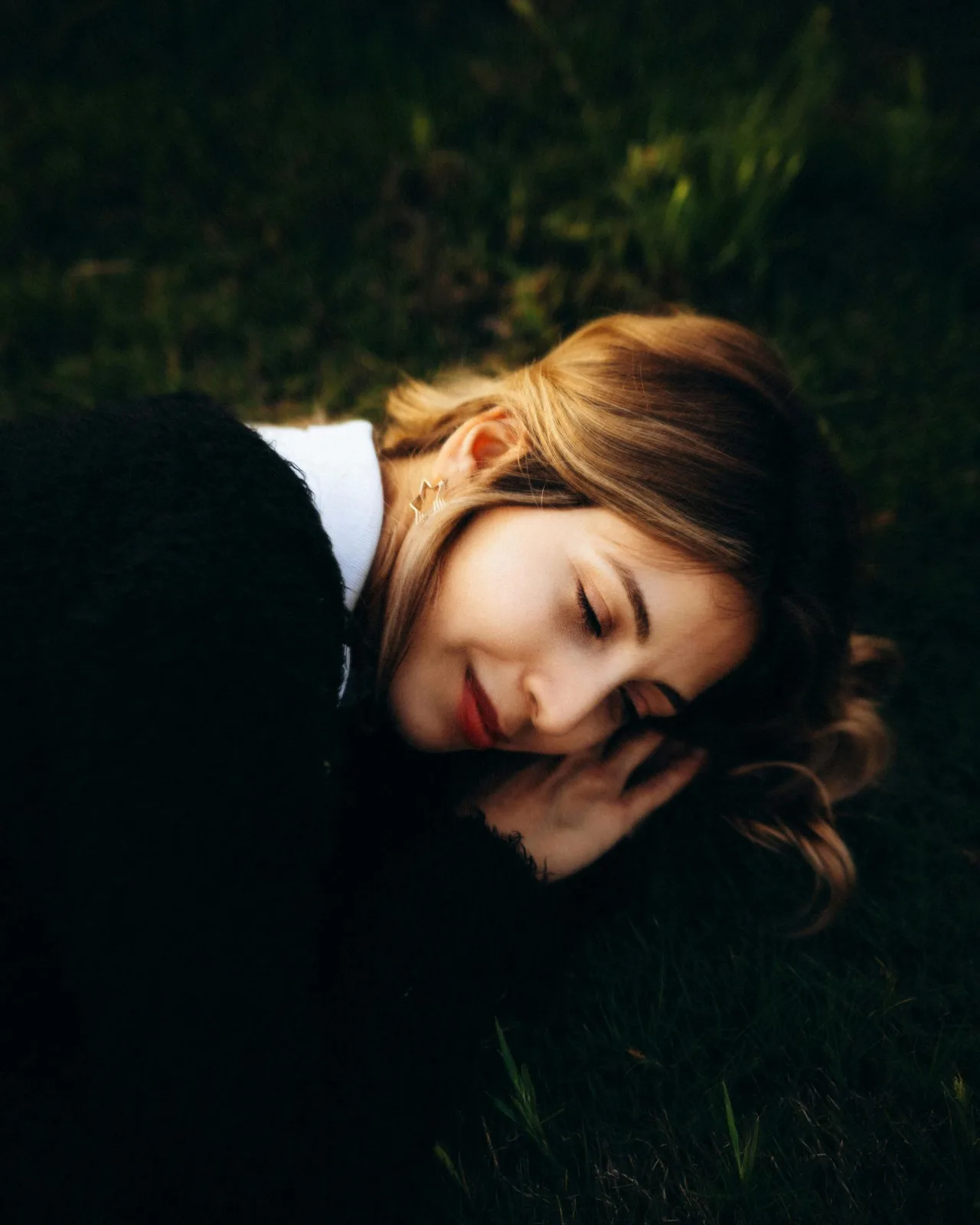 cô gái mặc áo đen nằm gối đầu lên tay và mỉm cười